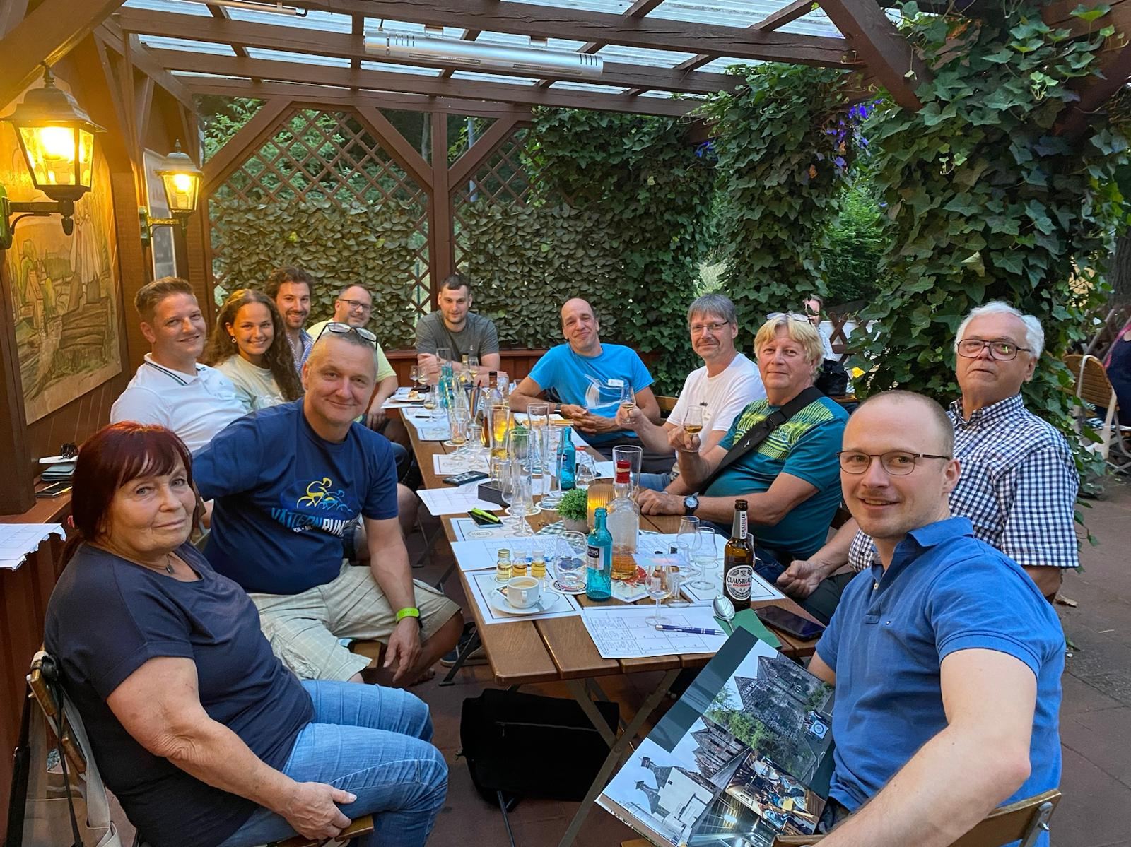 Mitglieder des Clubs an einer gedeckten Tafel im Biergarten des Gasthauses Trompeter